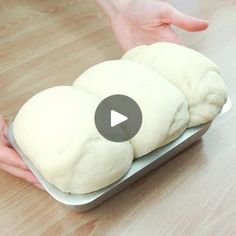 two buns sitting on top of a pan with one being held by someone's hand