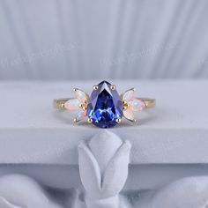 a tan gold ring with an oval blue sapphire surrounded by small white opal stones