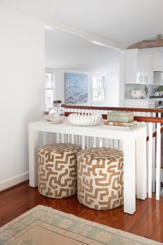 a white table with two stools and a bowl on it in a living room