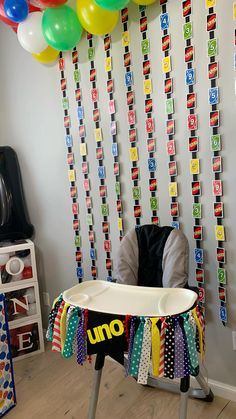 a table with some balloons on it in front of a wall that has ribbons hanging from it