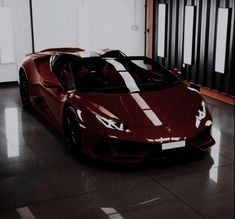 a red sports car is parked in a room with black and white stripes on it