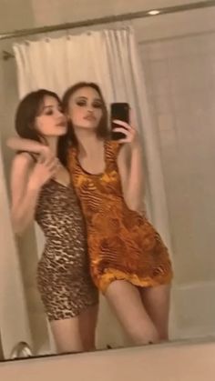 two women taking a selfie in front of a mirror