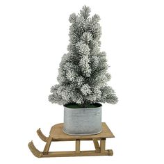 a small christmas tree in a metal pot on a wooden sled with snow flakes