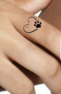 a woman's hand with a dog paw tattoo on her left ring and the word love written in black ink