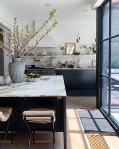 a large kitchen with marble counter tops and black cabinets, along with glass doors leading to an outdoor deck