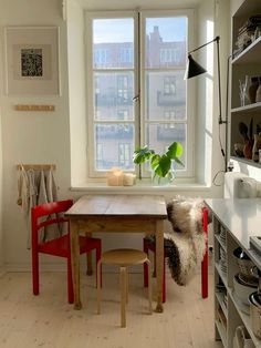 a kitchen table with two chairs and a potted plant in the window sill