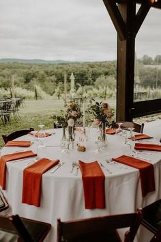 the table is set with orange napkins and place settings