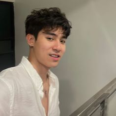 a young man in a white shirt is standing on the stairs and looking at the camera