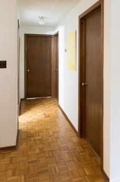 an empty hallway with wooden doors and hard wood flooring