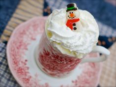 a cup filled with whipped cream and a small snowman decoration on top of it