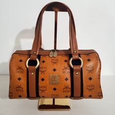 Shop jachzette09's closet or find the perfect look from millions of stylists. Fast shipping and buyer protection. Vintage MCM Top Handle Bag Size: Small Measurement: 12.5" (L) x 6" (H) Color: Brown Printed Visetos Antiqued Gold Brass Hardware Leather Trim Flat Handles Leather Trim Embellishment Logo Jacquard Lining & Three Interior Pockets Zip Closure at Top White Tag - Made in Korea NO DUST BAG Note: Please understand that this bag have been pre-owned, used and loved over many years and will Brown Monogram Canvas Bag With Detachable Strap, Elegant Brown Monogram Canvas Shoulder Bag, Brown Monogram Canvas Top Handle Shoulder Bag, Evening Shoulder Bag In Monogram Canvas, High-end Brown Bags With Leather Handles, High-end Brown Bag With Leather Handles, Brown Monogram Canvas Bag With Top Carry Handle, Luxury Brown Satchel For Shopping, High-end Brown Satchel Shoulder Bag