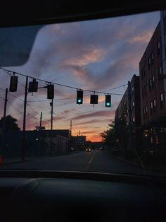 the sun is setting behind some buildings and traffic lights