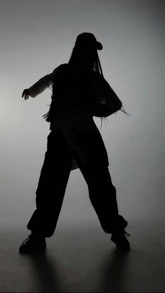 the silhouette of a person with long hair and a baseball cap is shown in front of a gray background