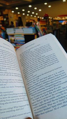 an open book sitting on top of a table next to a person's hand