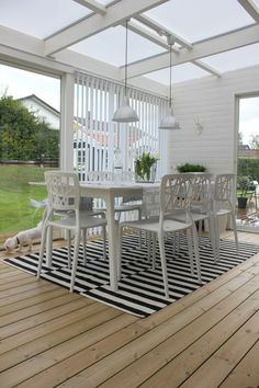 a white table and chairs sitting on top of a hard wood floored patio area