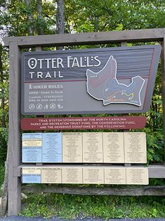 the sign for otter falls trail is posted in front of some trees and bushes with information about it