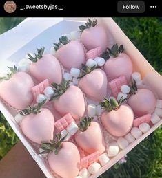 a box filled with pink and white chocolate covered in marshmallows on top of grass