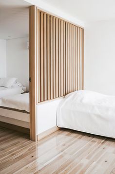 a white bed sitting in a bedroom next to a wooden paneled headboard on the wall