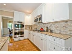 a kitchen with white cabinets and granite counter tops, along with a stainless steel stove top oven