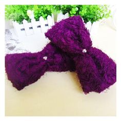 two pieces of purple yarn sitting on top of a table next to flowers and a white fence