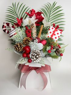 a christmas bouquet with pine cones, holly berries and other holiday decorations in a gift box