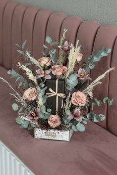 an arrangement of flowers and foliage on a bench