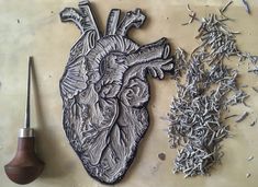 a metal heart next to a pipe and some shavings on a counter top