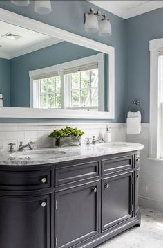 a bathroom with two sinks and a large mirror over it's counter top in front of a window