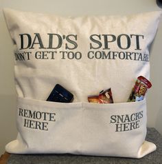 a pillow that has some snacks in it and the words dad's spot don't get too comfortable