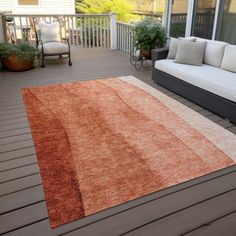 an orange and white rug on a wooden deck next to a couch, chair and table