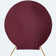 a round table with gold legs and a maroon cloth covering it