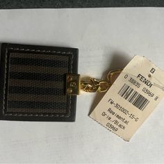 a tag attached to a leather wallet with a gold keychain hanging from it