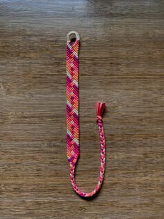 a pink and white lanyard on top of a wooden table