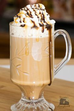 there is a drink with whipped cream and caramel on top in a glass mug