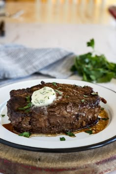 a piece of steak on a white plate with sauce and parsley garnish