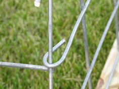 a close up of a metal fence with grass in the background