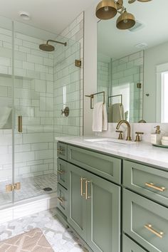 a bathroom with green cabinetry and gold hardware on the vanity, along with a walk in shower