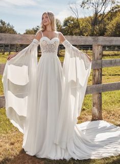 a woman in a white wedding dress standing next to a fence