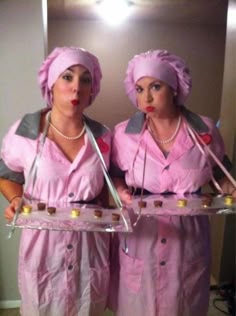 two women dressed in pink holding trays of food