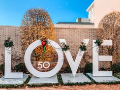 a sign that says love in front of a brick wall with wreaths on it