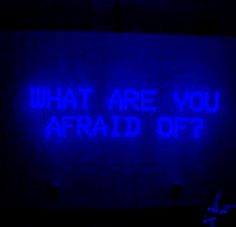 a blue sign that says what are you afraid of? in front of a dark background