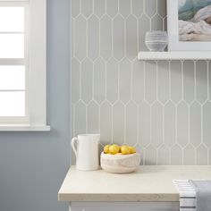 a bowl of lemons sitting on top of a counter next to a white cup