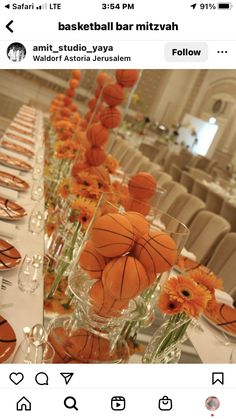 a table with orange flowers and basketballs in vases on top of the tables