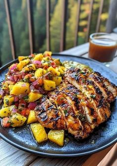 grilled chicken with pineapple salsa on a blue plate next to a glass of orange juice