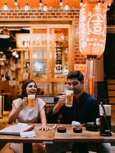 two people sitting at a table drinking beer