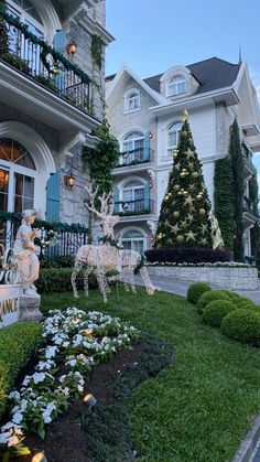 a christmas display in front of a large house with trees and decorations on the lawn