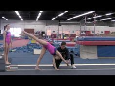 two people are doing gymnastics in an indoor gym with one person on the floor and another standing up