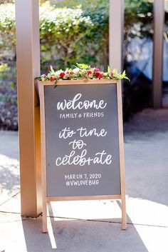 a welcome sign with flowers and greenery on it