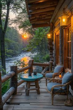 a porch with two chairs and a table on it next to a river at sunset