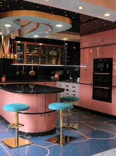 a kitchen with pink cabinets and blue stools in the center, along with black counter tops